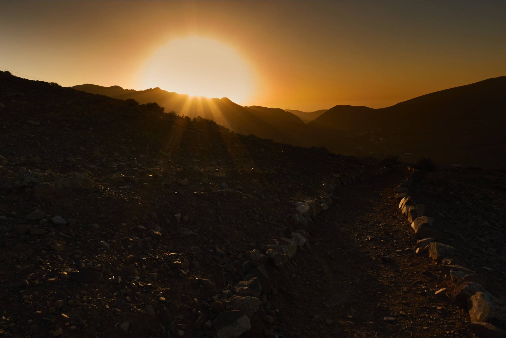 Hinunter nach Vega de Río Palmas bei Sonnenuntergang – der Feuerball versinkt hinter dem Höhenzug aus dem Pico Lima (629 m), Risco Blanco (618 m) und Pico de la Muda (535 m).