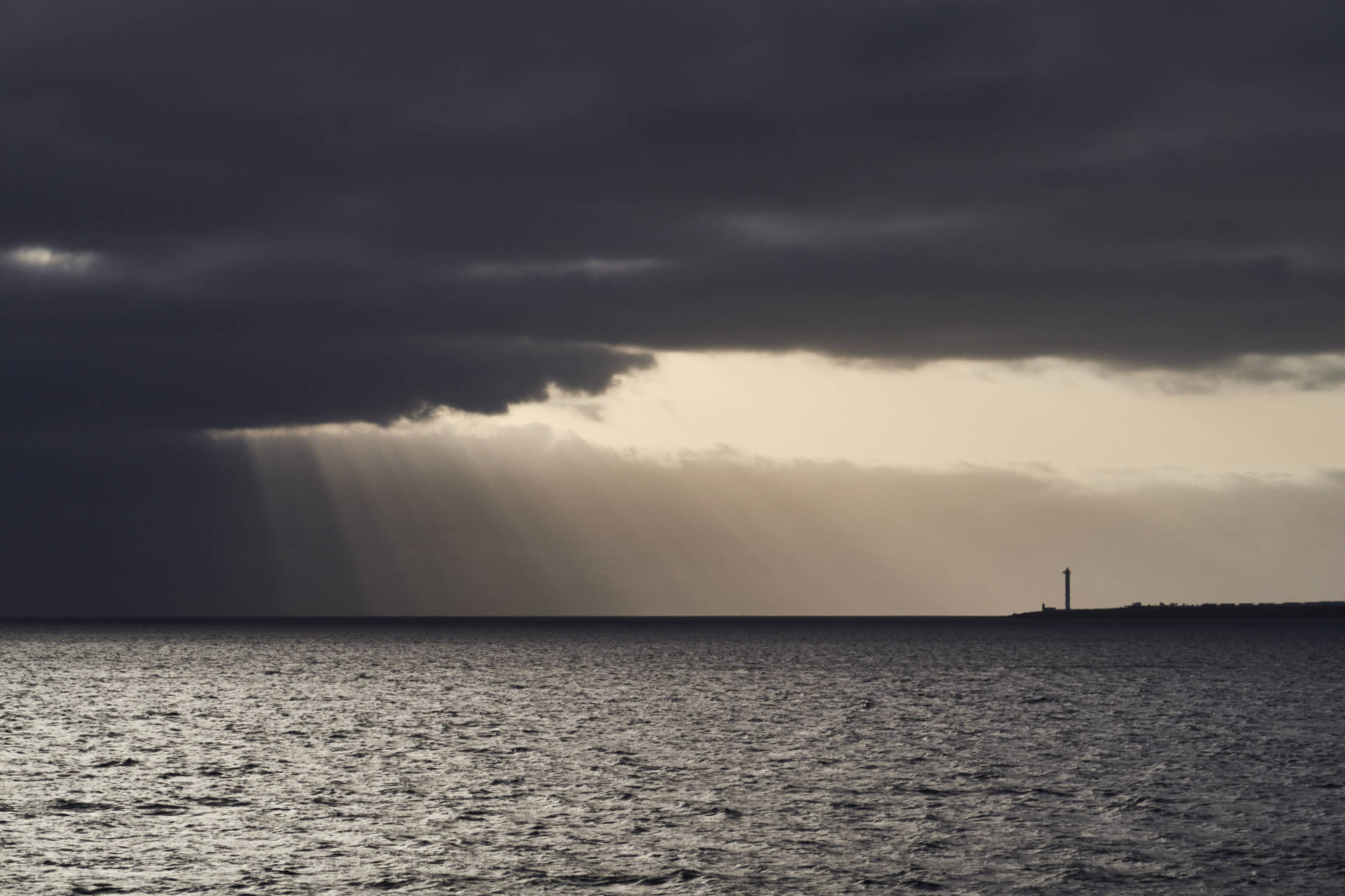 Blick von der Fähre bei Sonnenuntergang auf den Faro de Pechiguera auf Lanzarote.