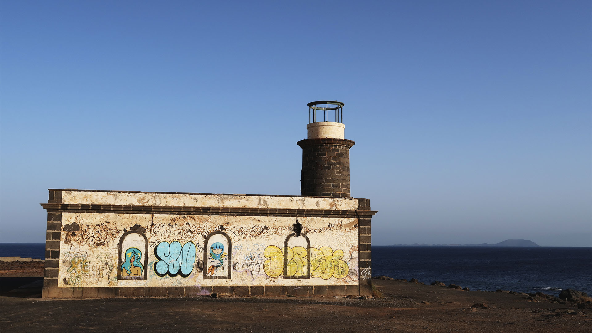 Der alte Leuchtturm Faro Punta de Pechiguera Lanzarote. Im Hintergrund zeichnet sich die Isla de Lobos ab.